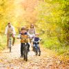 Young family in warm clothes cycling in autumn park